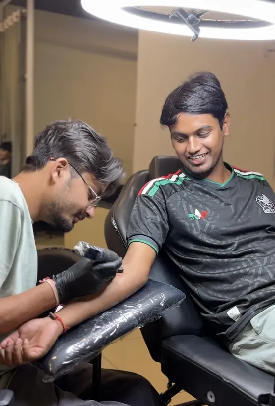 Client smiling during a tattoo session at The Kala Culture Tattoos, Vadodara